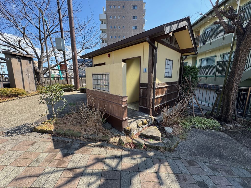 A small building with public toilets, surrounded by a small garden.