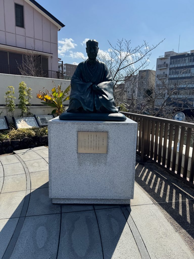 A bronze statue of the poet Bashō overlooking the intersection of two rivers.