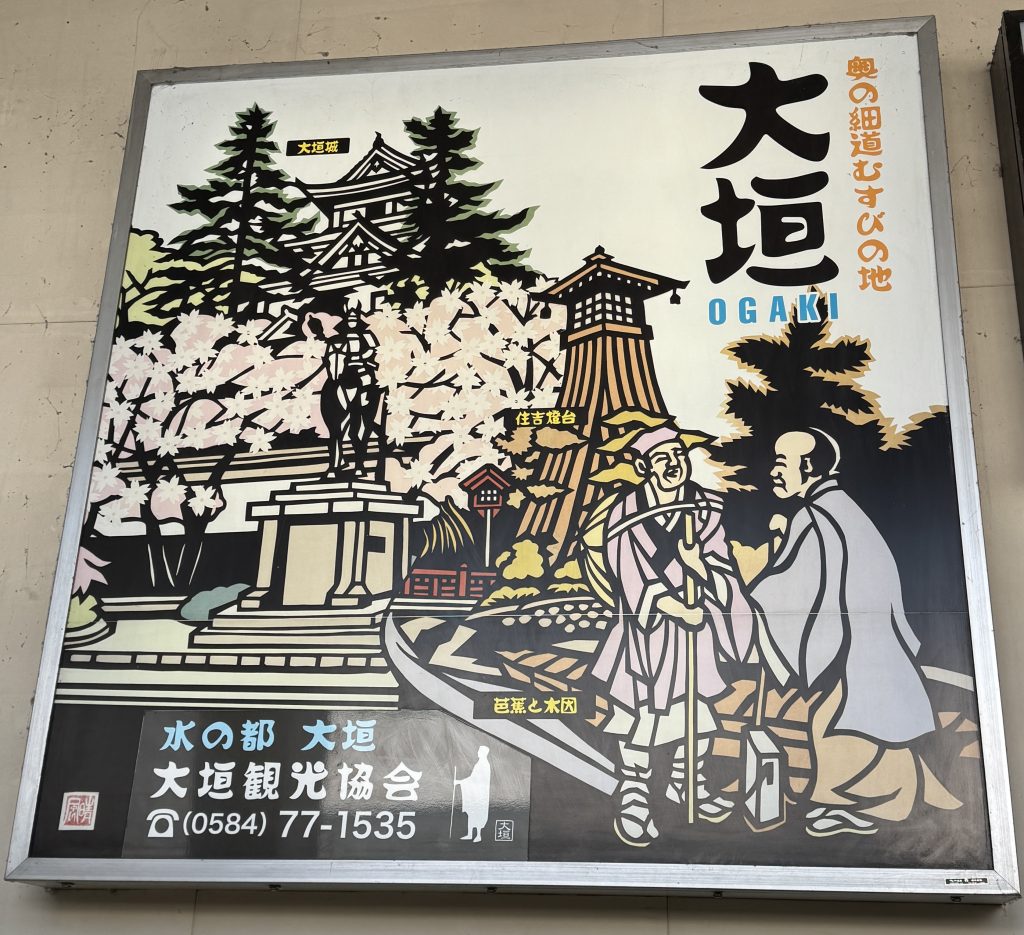 A sign advertising the sights of Ogaki, Japan, including a castle, a man on horseback, a fire tower, cherry blossoms, and a representation of the haiku poet Bashō
